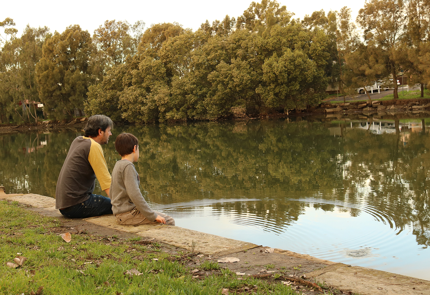 Father and son sitting by the lake